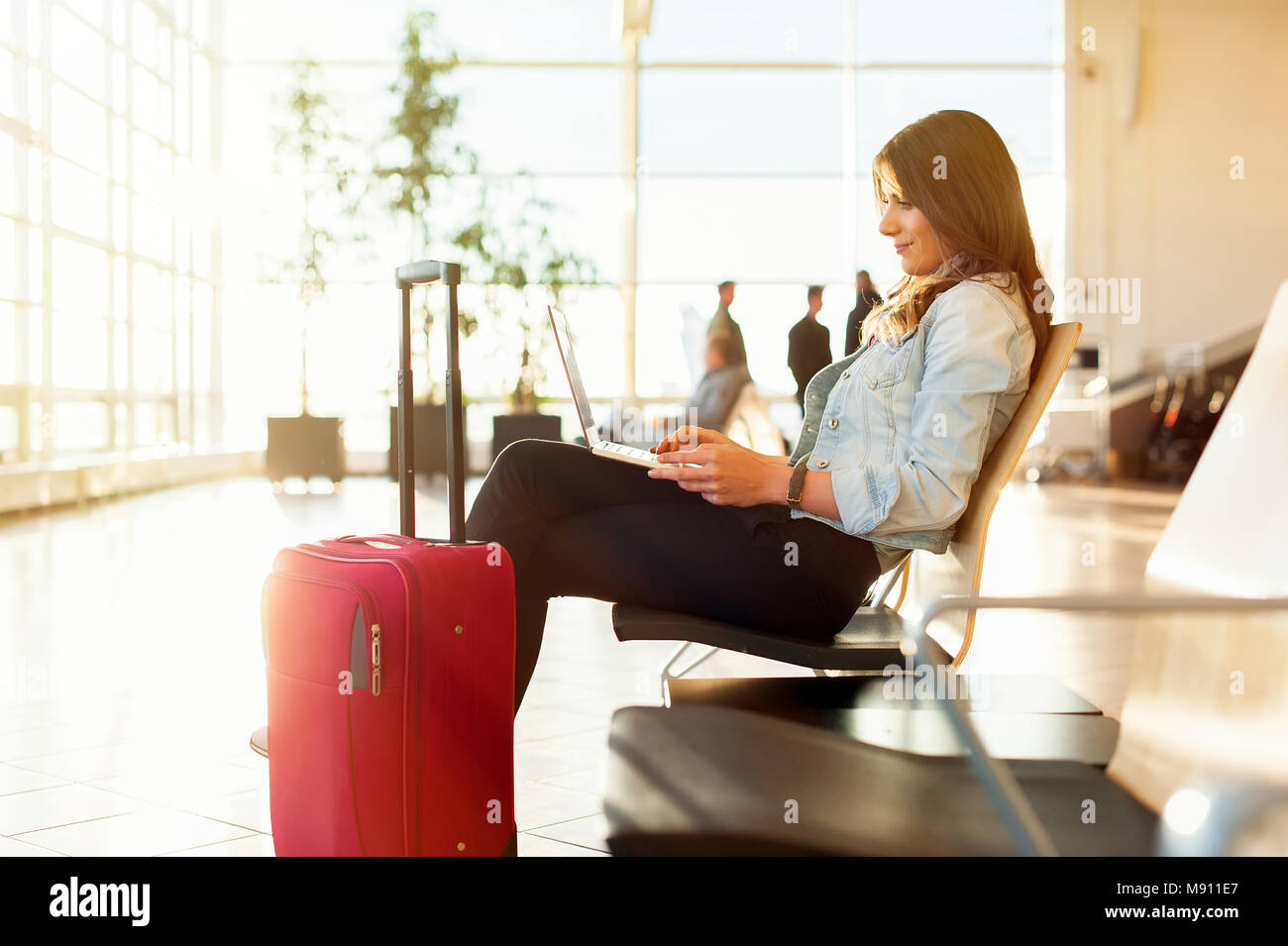 Flughafen jungen weiblichen Passagier auf Smartphone und Laptop im Terminal Hall beim Warten auf ihren Flug Stockfoto