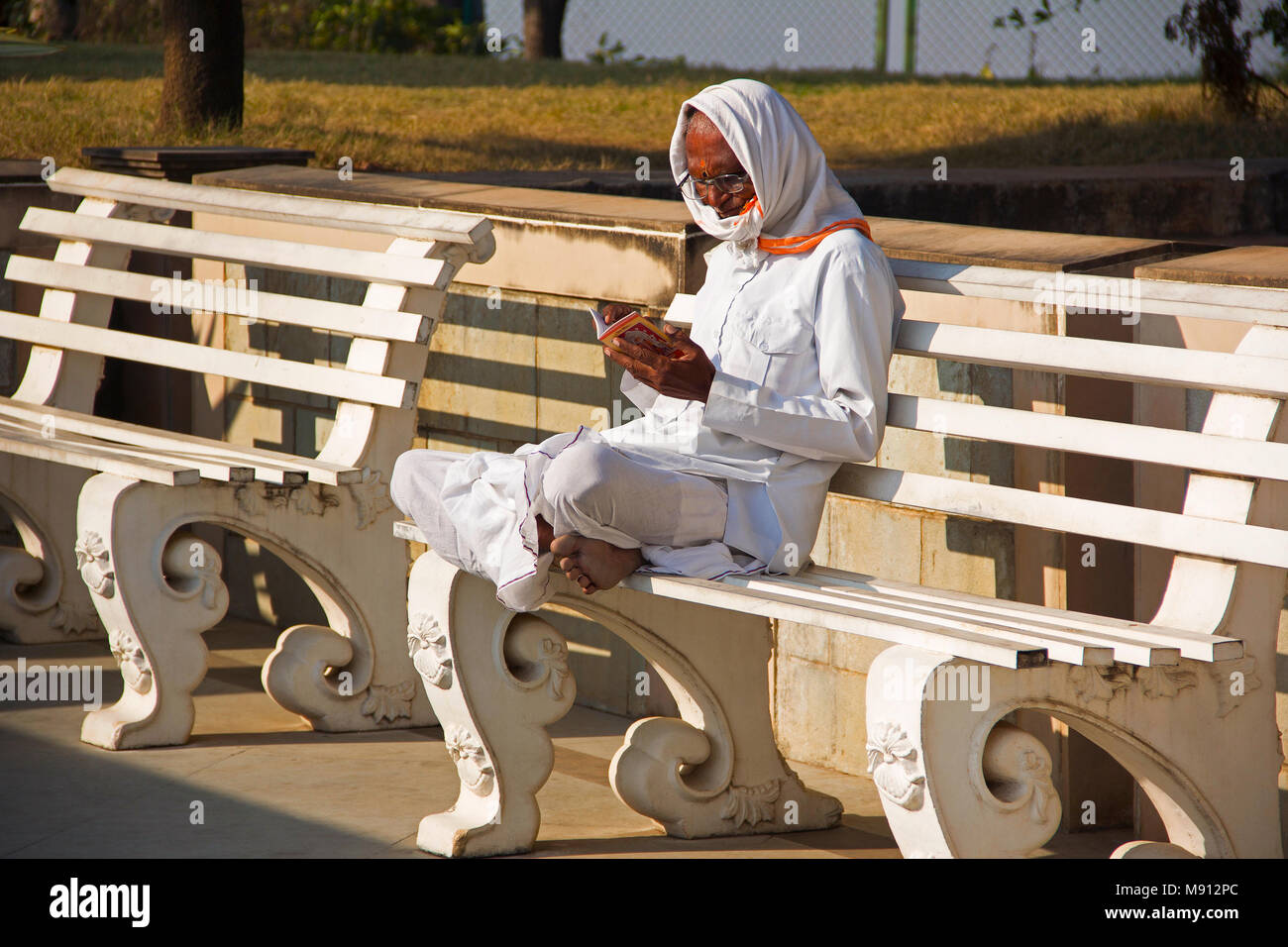 Alter Mann ein Buch lesen bei Ganapati Birla Tempel, Somatane Mautstelle in Pune Stockfoto