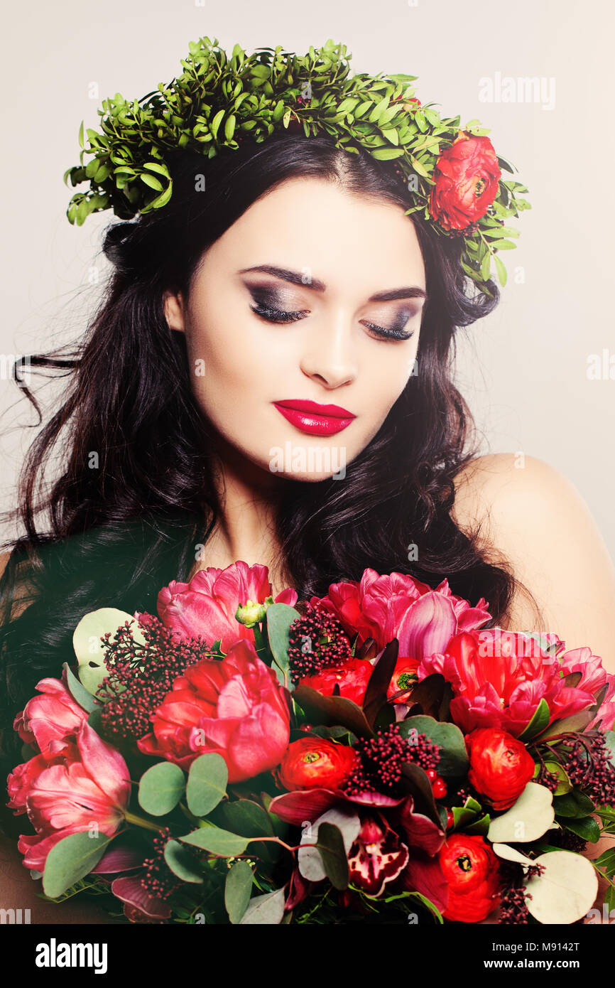 Beauty Fashion Portrait. Schöne Frau mit lockigem Haar, Make-up und Blumen Stockfoto