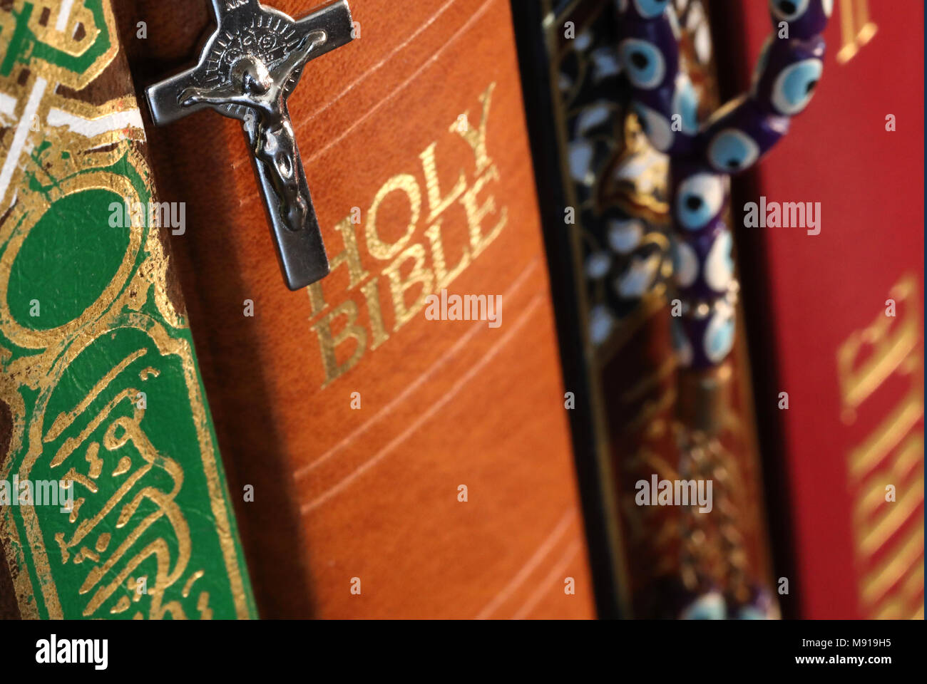 Stapel der heiligen Bücher: Bibel und Koran. Christentum und Islam. Kruzifix und Gebet Perlen. Interreligiöse Symbole. Stockfoto