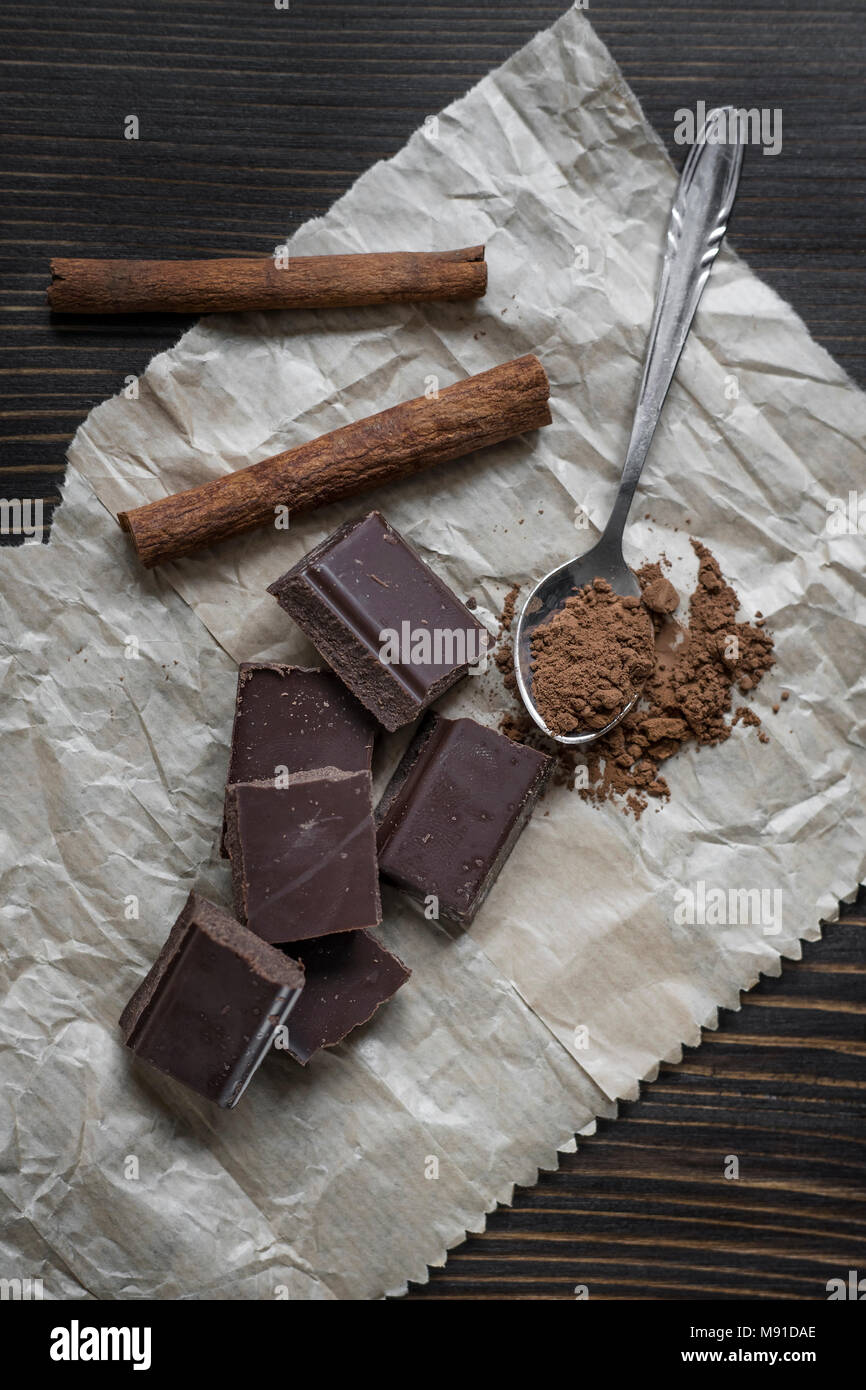 Gebrochene Schokolade und Gewürzen auf hölzernen Tisch. Von oben Stockfoto