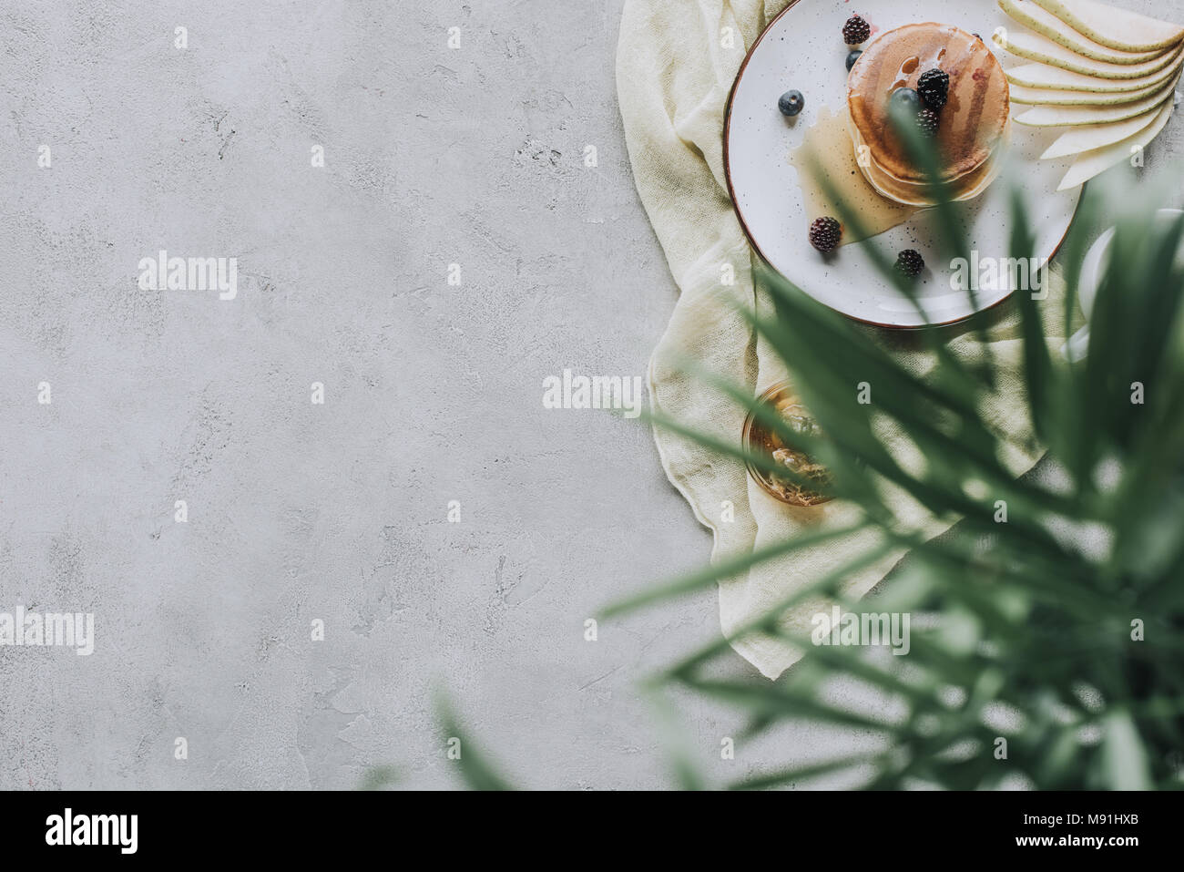 Selektiver Fokus der leckere hausgemachte Pfannkuchen mit Honig und Beeren auf Grau Stockfoto