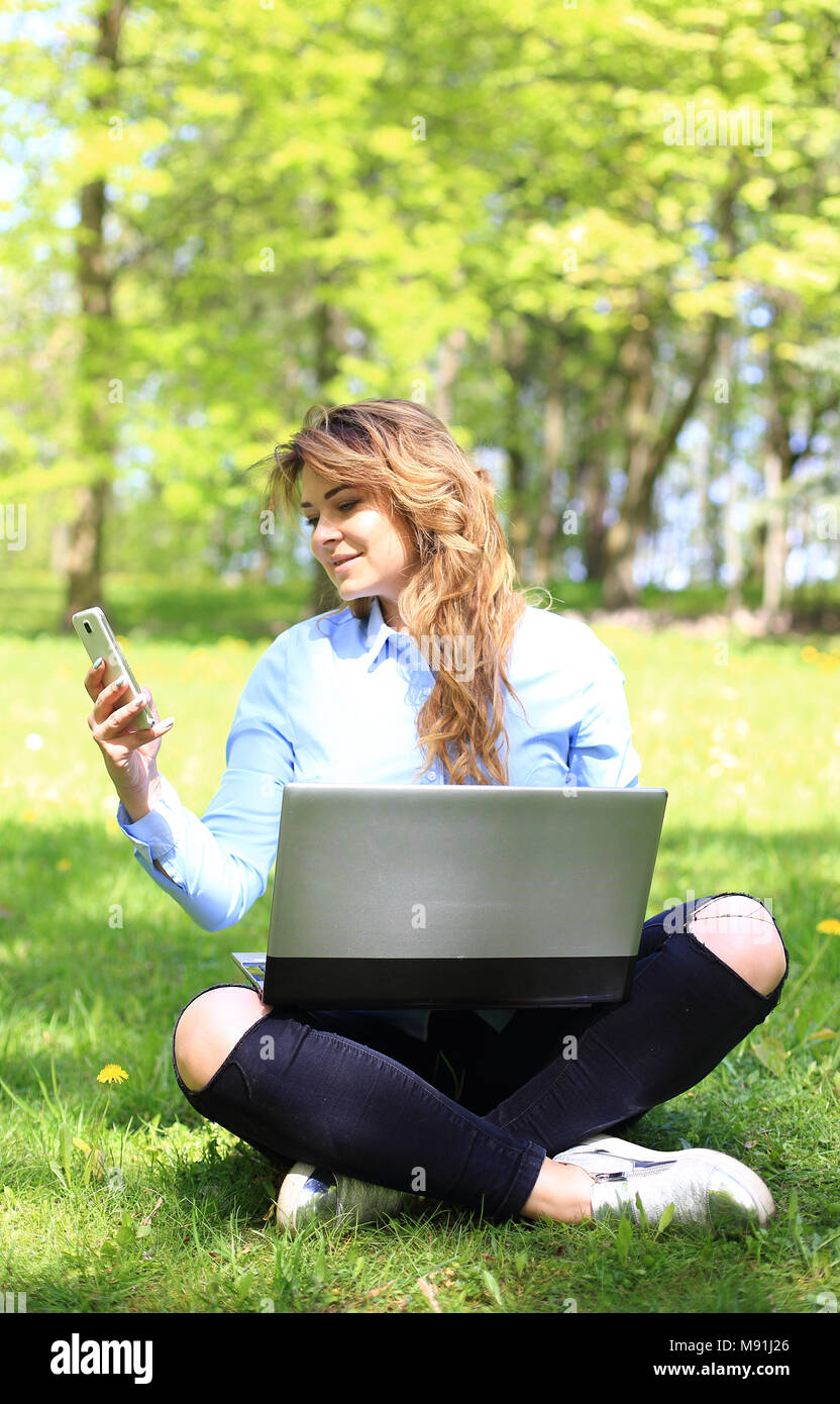 Junge hübsche Mädchen Arbeiten am Laptop im Freien, liegen auf Gras, kaukasische 20 Jahre alt Stockfoto