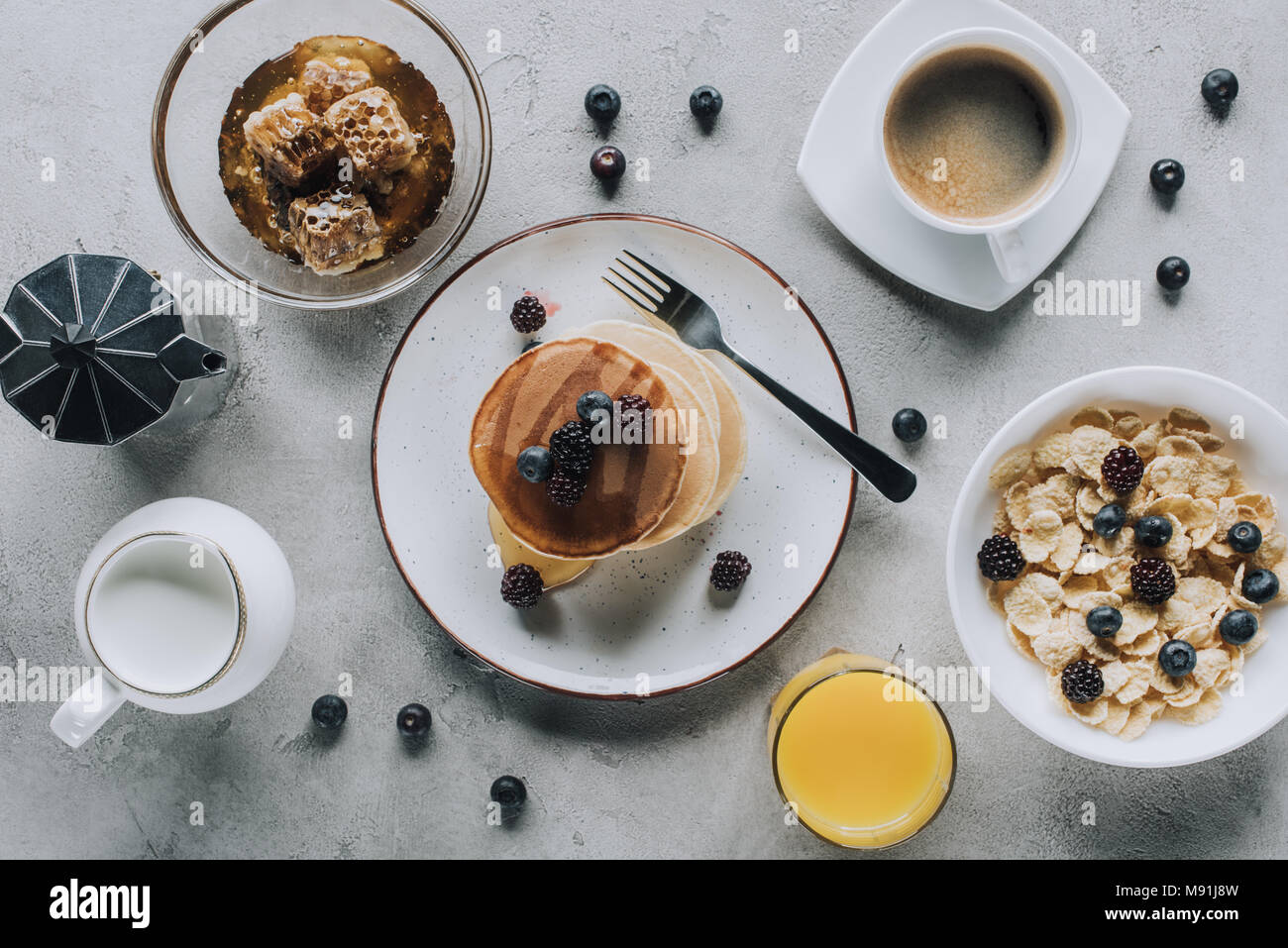 Blick von oben auf die lecker gesundes Frühstück mit Pfannkuchen und Müsli auf Grau Stockfoto