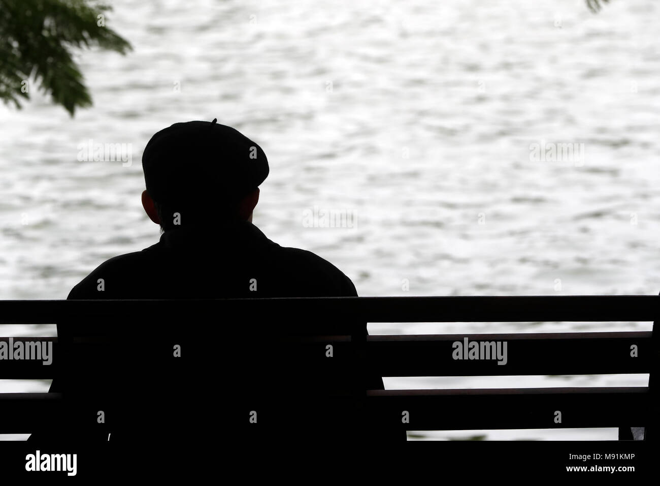 Mann sitzt auf einer Bank vor der Hoan Kiem See. Hanoi. Vietnam. Stockfoto