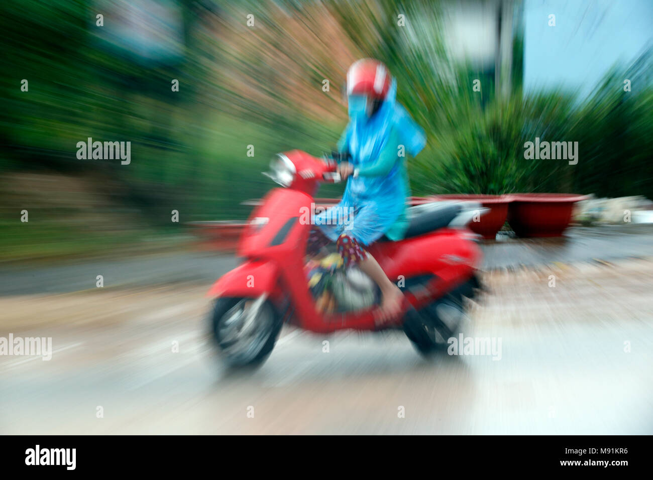 Schwere Monsunregen. Frau, die ein rotes Motorrad. Phu Quoc. Vietnam. Stockfoto