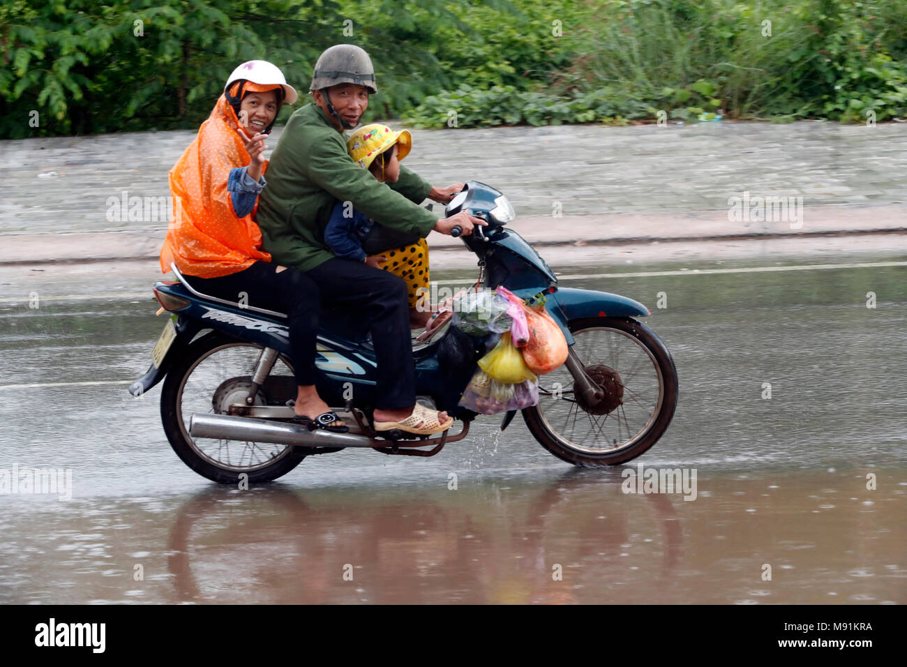Schwere Monsunregen. Familie fährt ein Motorrad. Phu Quoc. Vietnam. Stockfoto