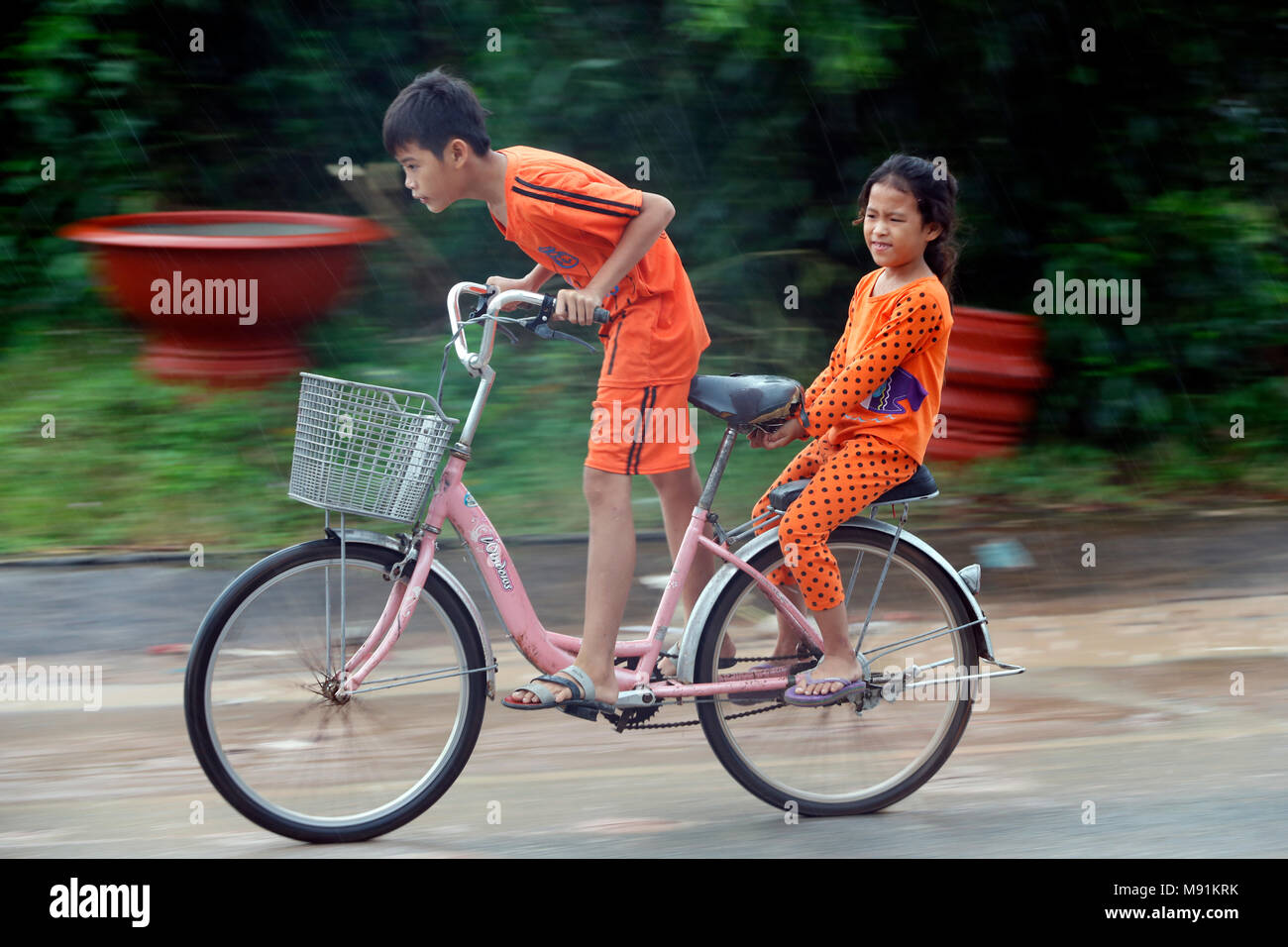 Schwere Monsunregen. Zwei Jungen fahren ein Fahrrad. Phu Quoc. Vietnam. Stockfoto