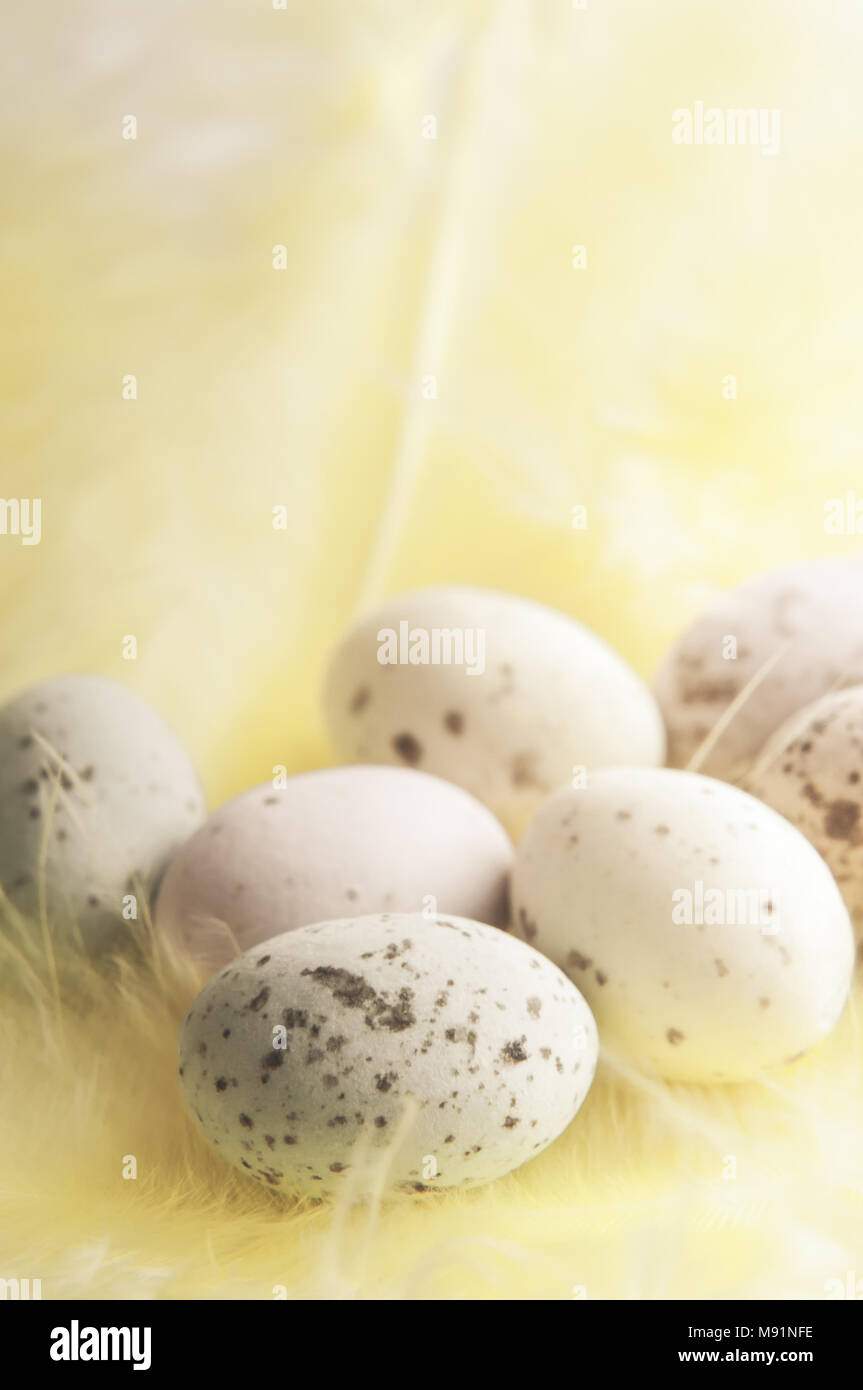 Eine Auswahl an kleinen gefleckten harte Schale Ostern Eier Süßigkeiten in Pastellfarben, ruht auf einem flufffy Gelbe Feder mit Filter Effekte angewendet. Stockfoto