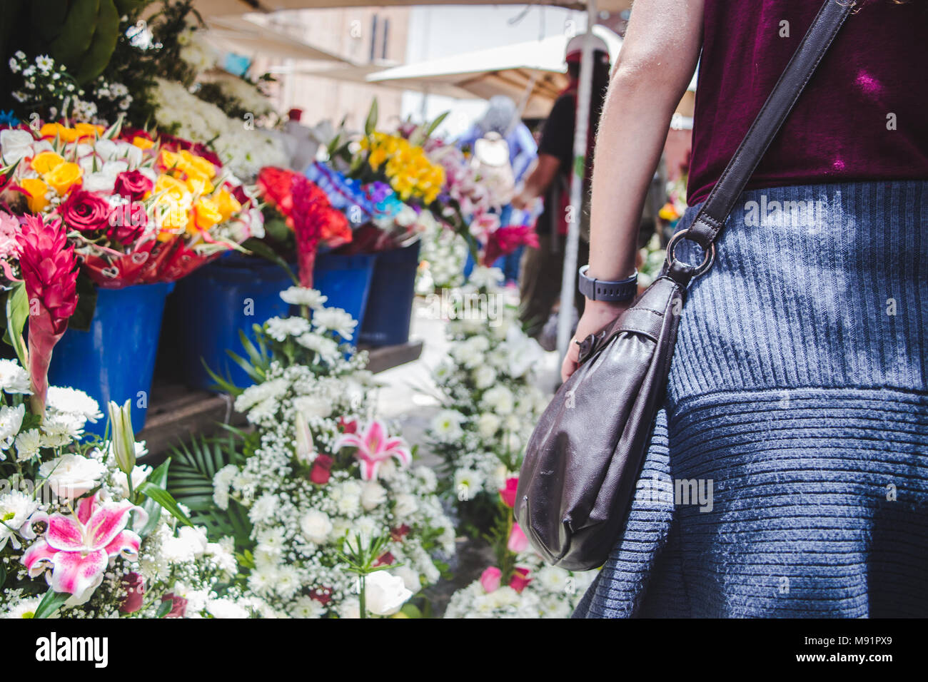 Frau geht vorbei an bunten exotischen Blumen auf Verkauf in Blumentöpfe in einem Blumenmarkt in Cuenca, Ecuador Stockfoto