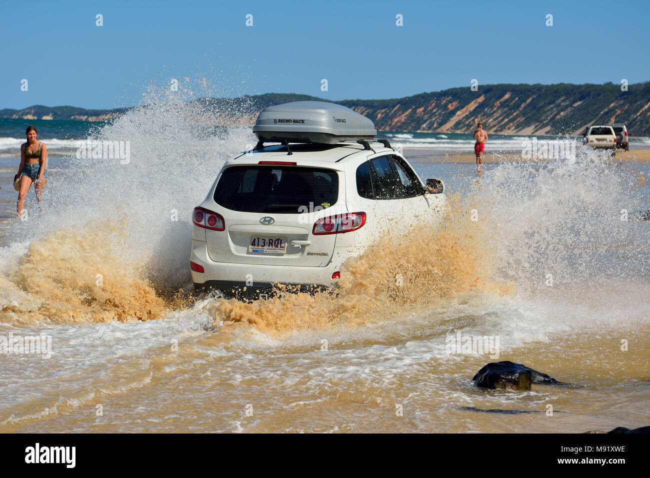 Rainbow Beach, Queensland, Australien - 23. Dezember 2017. 4WD Hyundai Auto über eine Auswaschung fahren im Meer spritzt Wasser auf Rainbow Beach in Quee Stockfoto