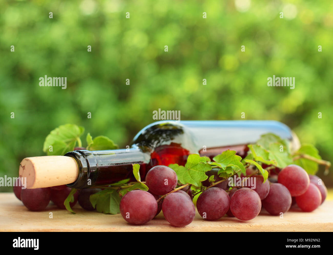 Flasche Wein, rote Traube und grüne Blätter - Hintergrund Stockfoto
