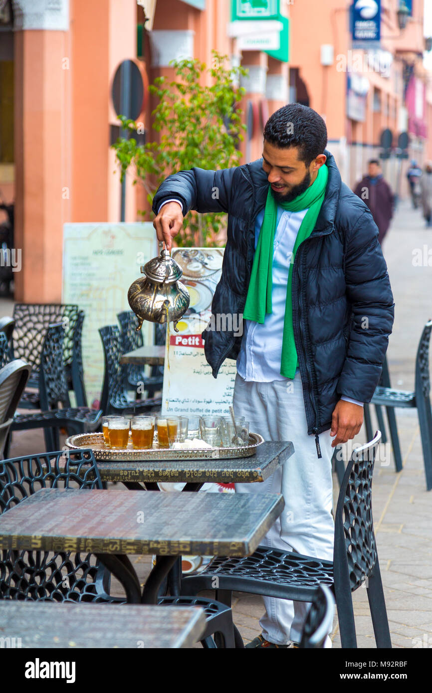 Man gießt marokkanischen Pfefferminztee aus einem Metall Topf in der Straße, Marrakesch, Marokko Stockfoto