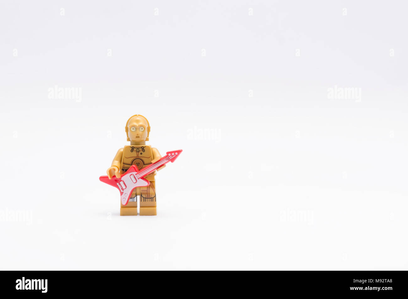 Lego c3po Minifigur Holding eine Gitarre mit Mikrofon, auf weißem Hintergrund. Stockfoto