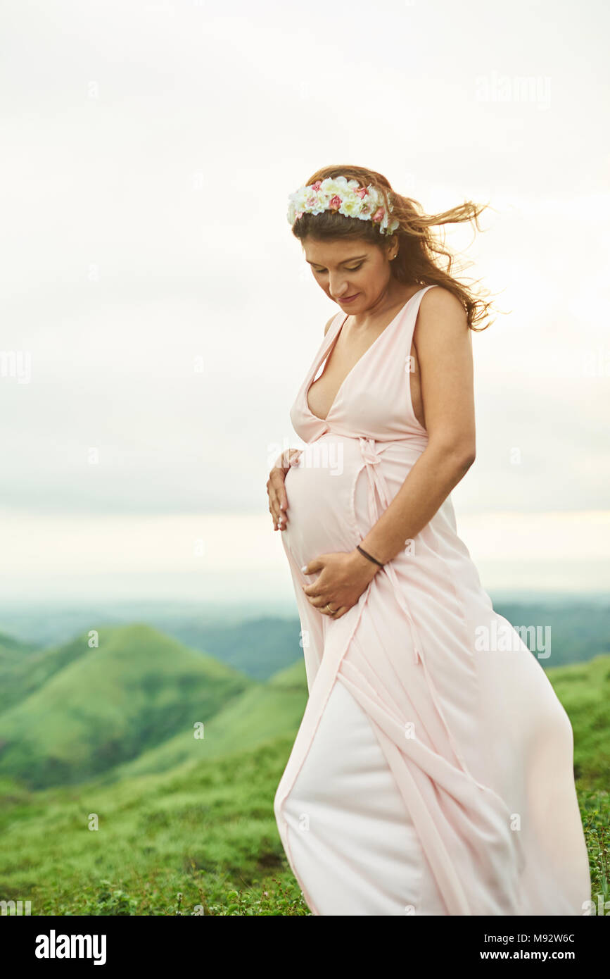 Eine junge schwangere Frau im rosa Kleid außerhalb Stockfoto