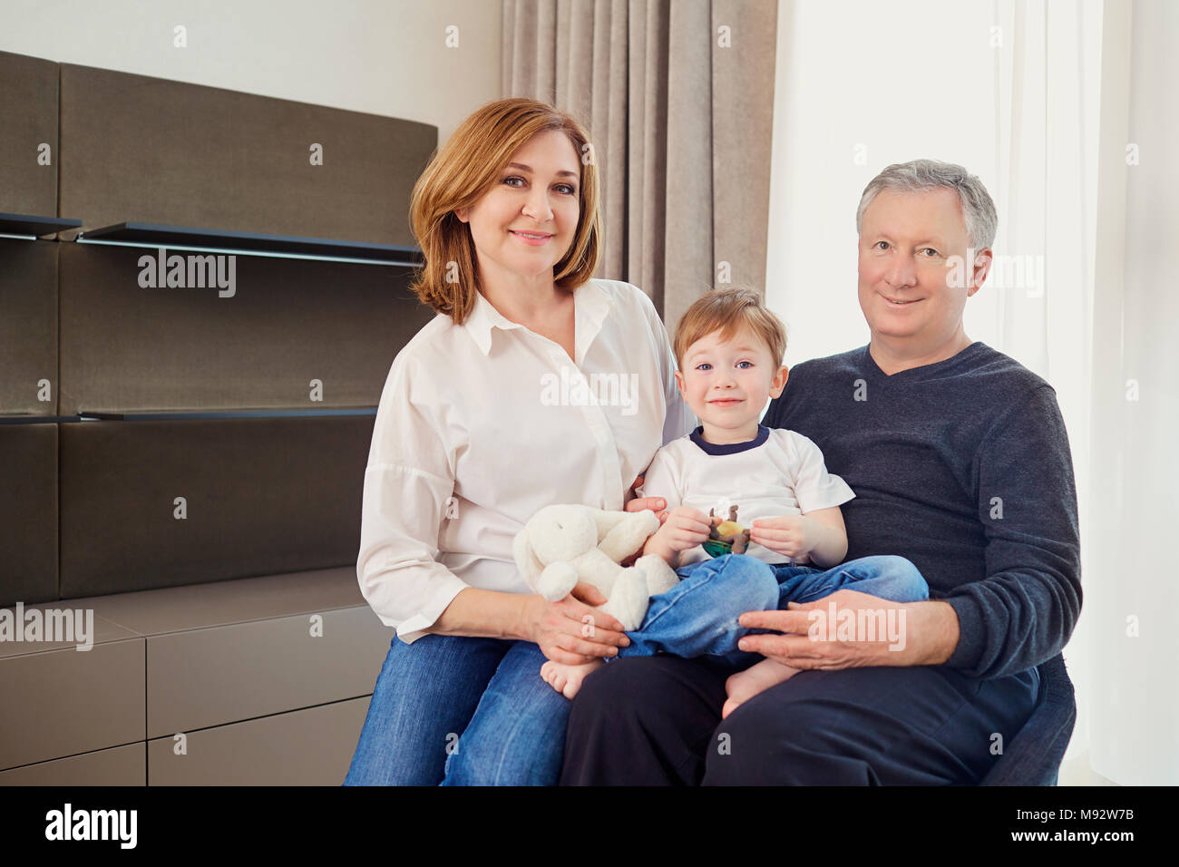 Großmutter und Großvater mit Enkel in einem Raum vor Stockfoto