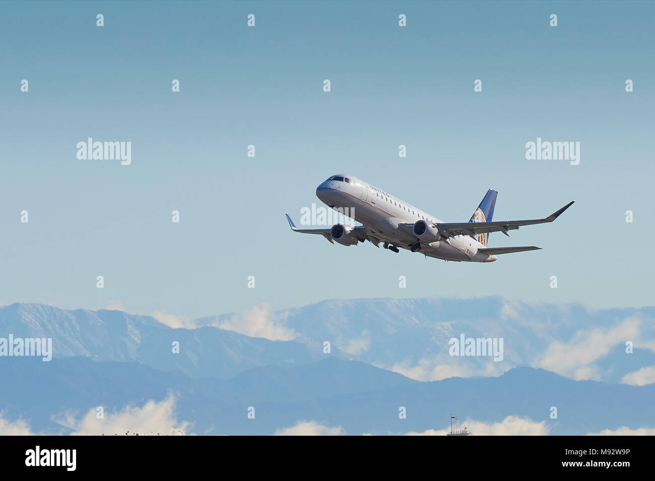 United Express, SkyWest, Embraer E-175 E-Jet, vom internationalen Flughafen Los Angeles, LAX, die schneebedeckten San Gabriel Berge dahinter. Stockfoto