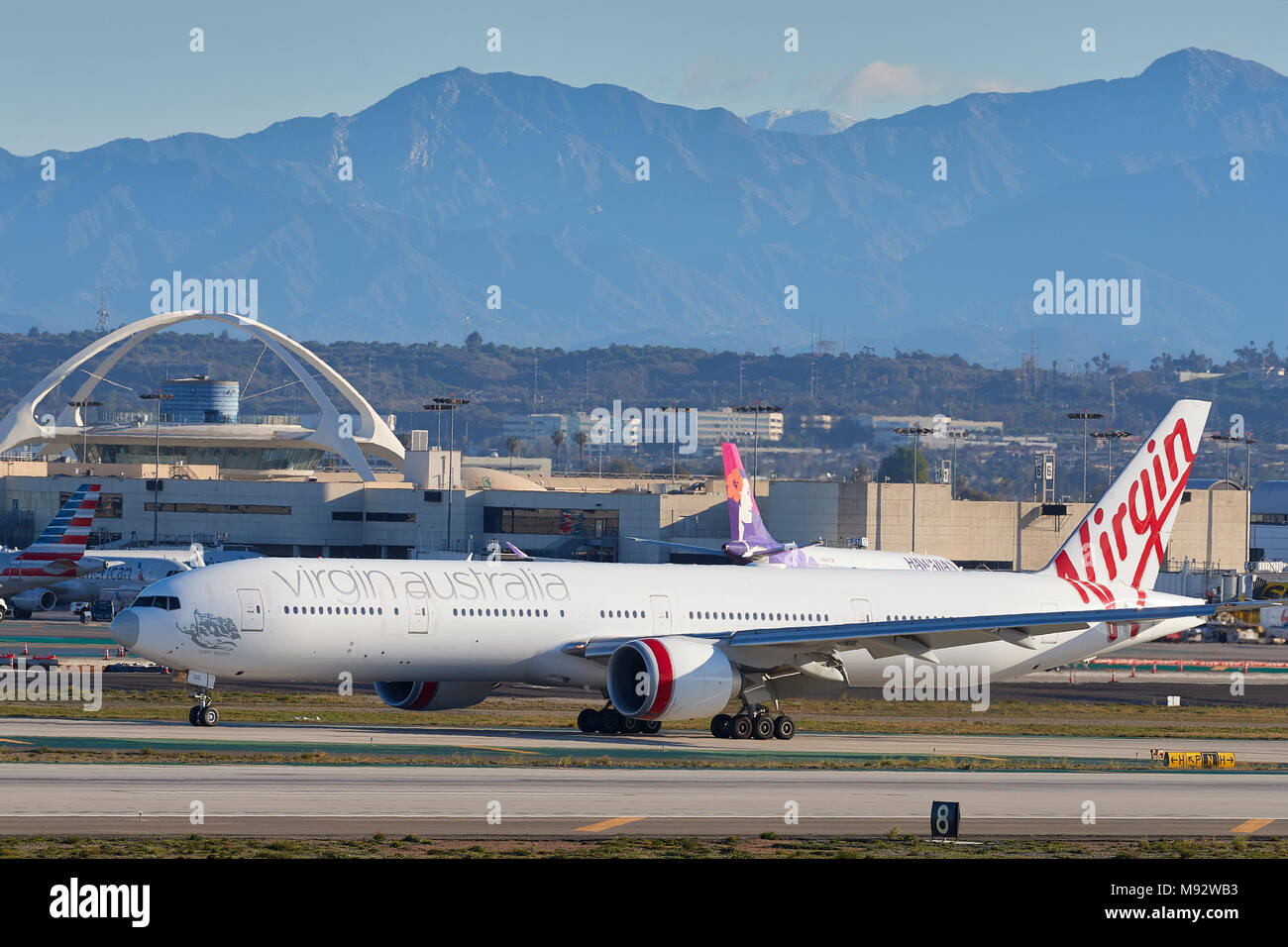 Jungfrau Australien Airlines Boeing 777-300Passenger Jet Ankunft in Los Angeles International Airport LAX. Die San Gabriel Berge dahinter. Stockfoto