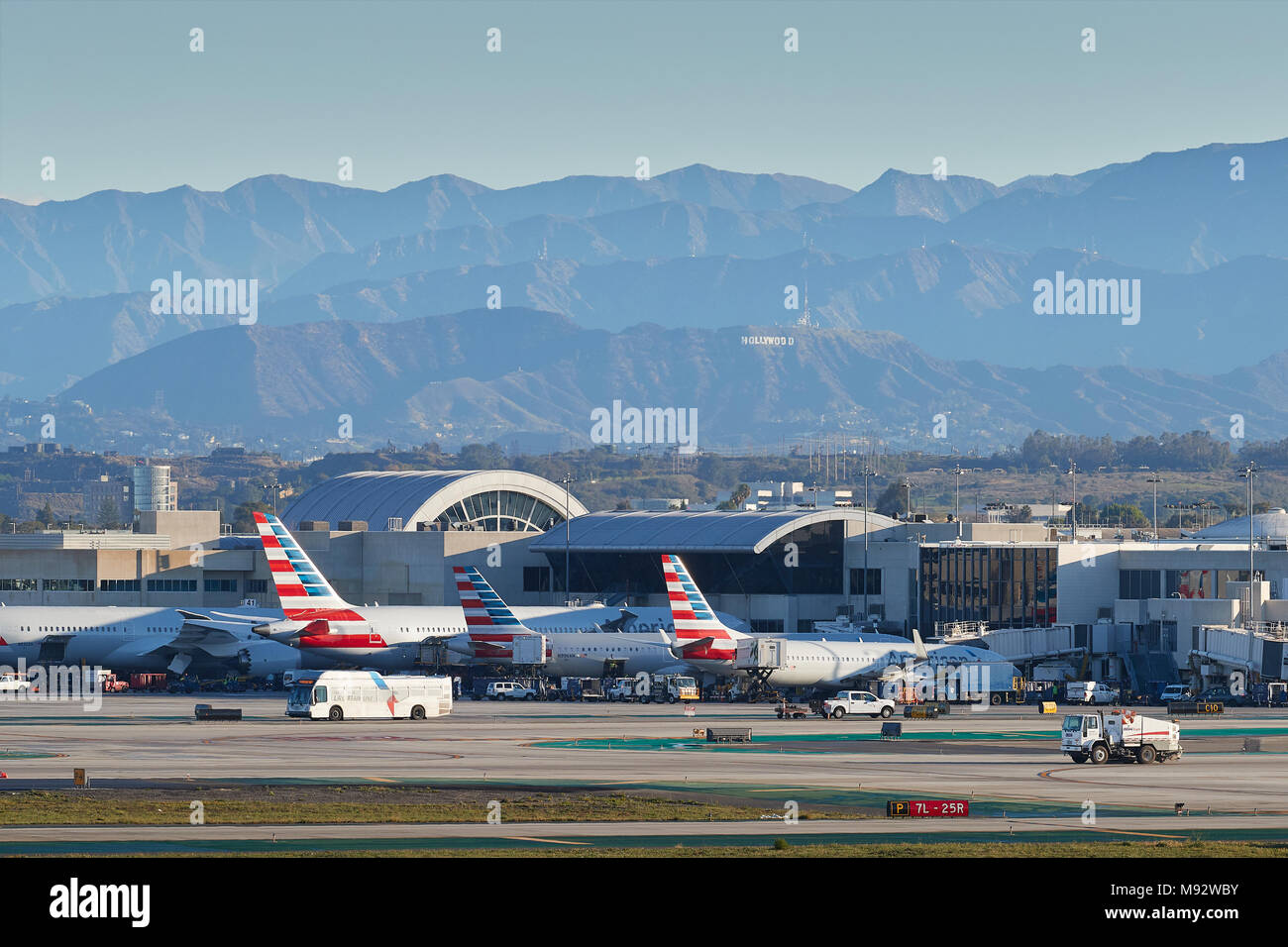 Geparkt American Airlines Passenger Jets in den frühen Morgenstunden am Los Angeles International Airport LAX. Das Hollywood Zeichen und die Berge dahinter. Stockfoto