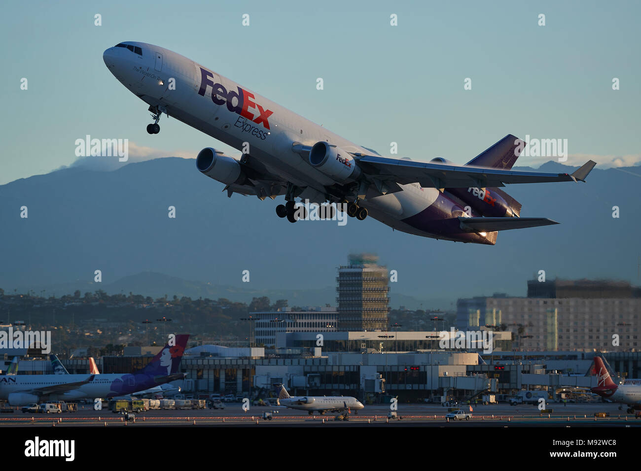 FedEx Express MD11 Cargo Jet vom Internationalen Flughafen Los Angeles, LAX, der Alte Air Traffic Control Tower im Hintergrund. Kalifornien, USA. Stockfoto