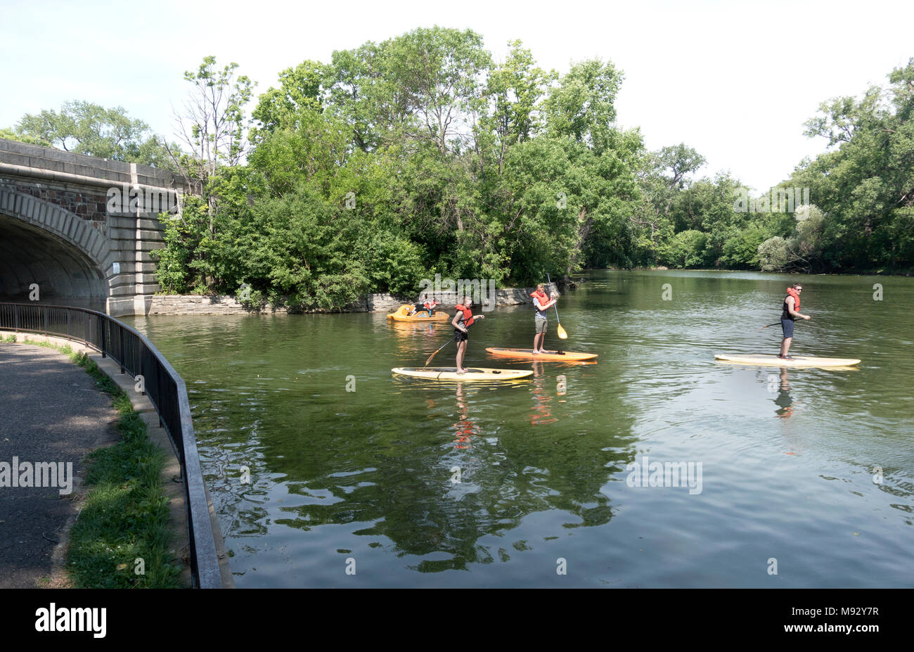 Teens auf paddleboards und feilbieten Boot bestanden hat, durch den Kanal zwischen Lake Calhoun und See von den Inseln Minneapolis Minnesota MN USA Stockfoto