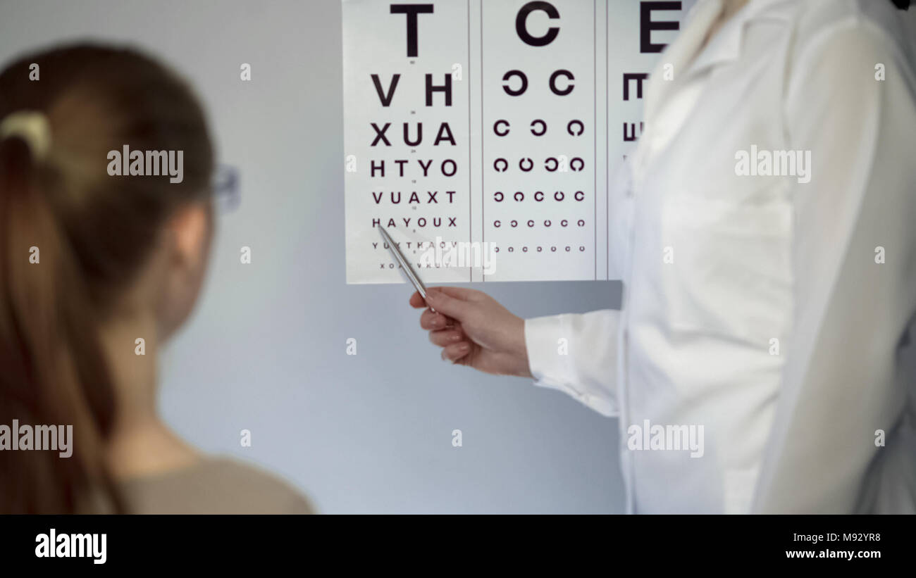 Schule Mädchen in Gläsern lesen während der medizinischen Checkup, Sehkraft Prüfung Stockfoto