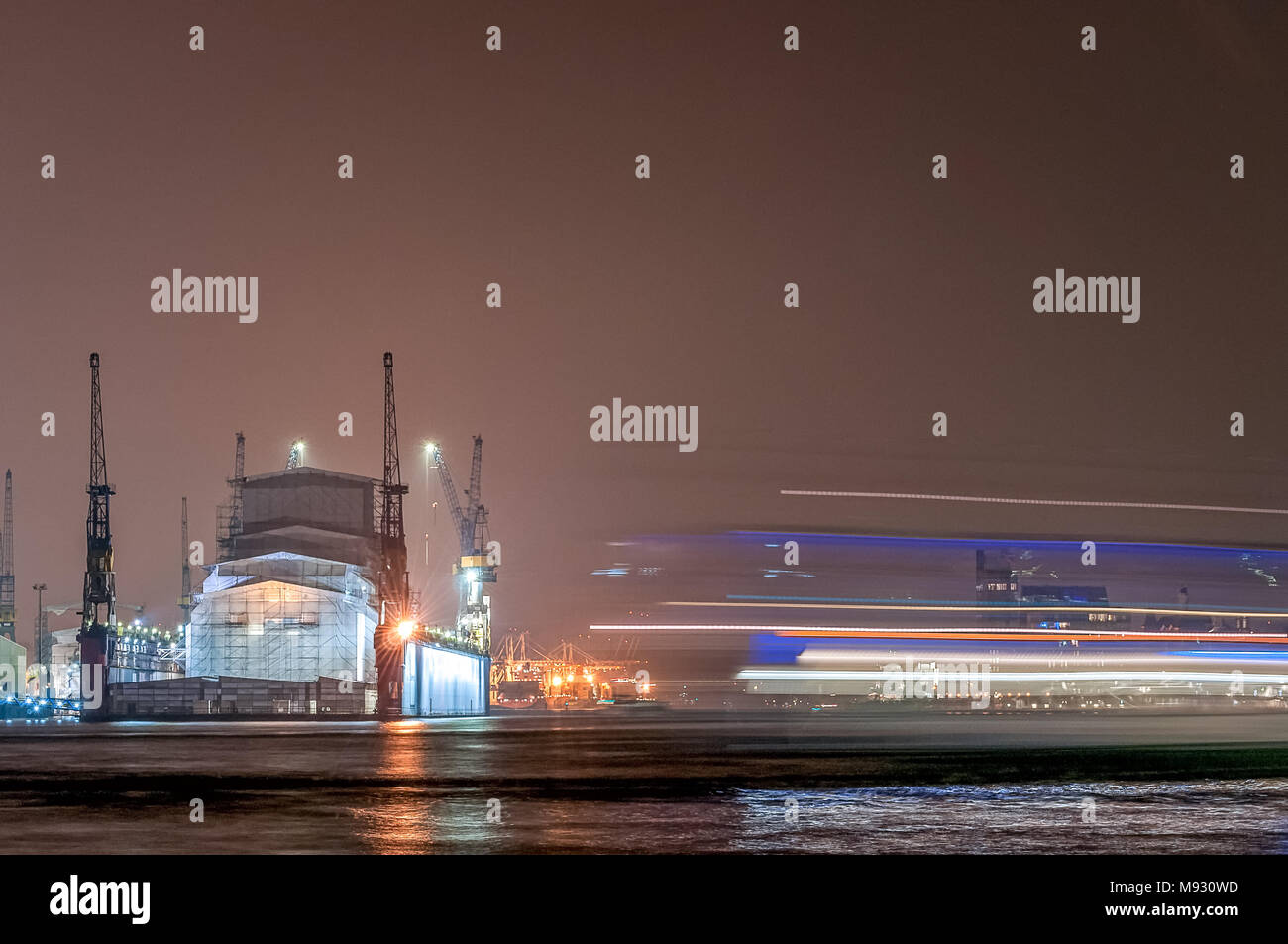Hamburg, Deutschland. 03. April 2014: Lange Exposition der Werft Blohm + Voss und Fähre in der Nacht. Stockfoto