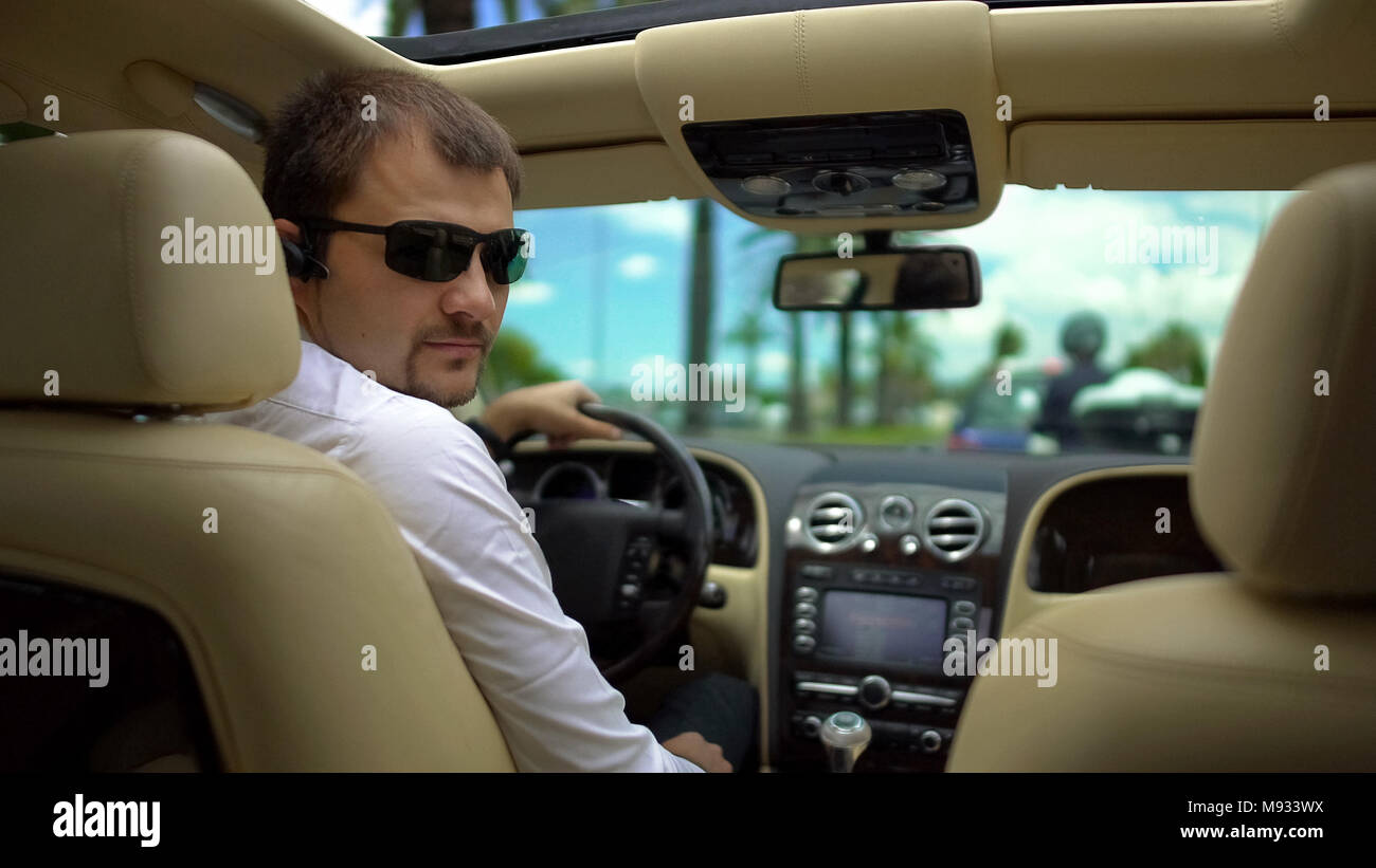 Zuversichtlich Fahrer in Sonnenbrille beobachten an der Rückseite des Sitzes, hören Chef Anweisungen Stockfoto