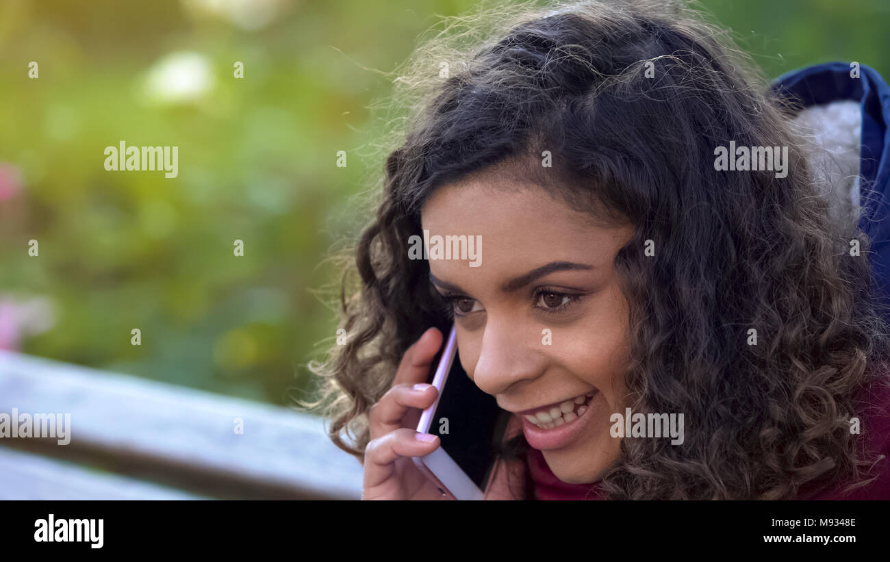 Curly biracial Frau aktiv sprechen über Smartphone, Gespräch mit Freund Stockfoto
