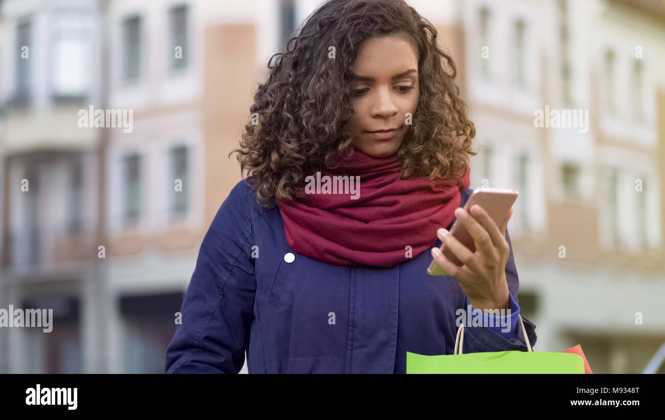 Hübsche Frau Wahl Geschenke online, Surfen im Web speichert auf dem Smartphone Stockfoto