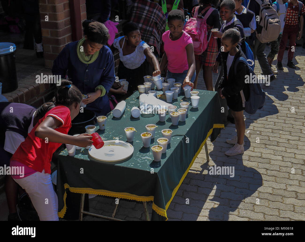 Johannesburg, Südafrika - Unbekannter unterprivilegierten Schule erhalten die Kinder essen Handouts für eine Suppenküche an ihrer Schule in der Stadt Bild in Stockfoto
