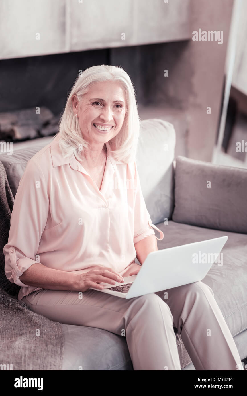 Ältere Frau und lächelnd Laptop auf den Knien zufrieden. Stockfoto
