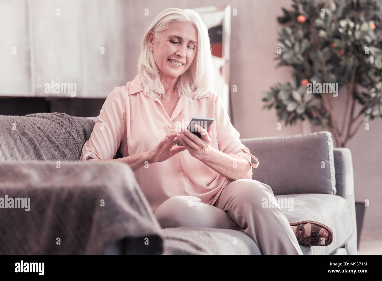 Smart grau behaarte Frau sitzen und über Ihr Handy. Stockfoto