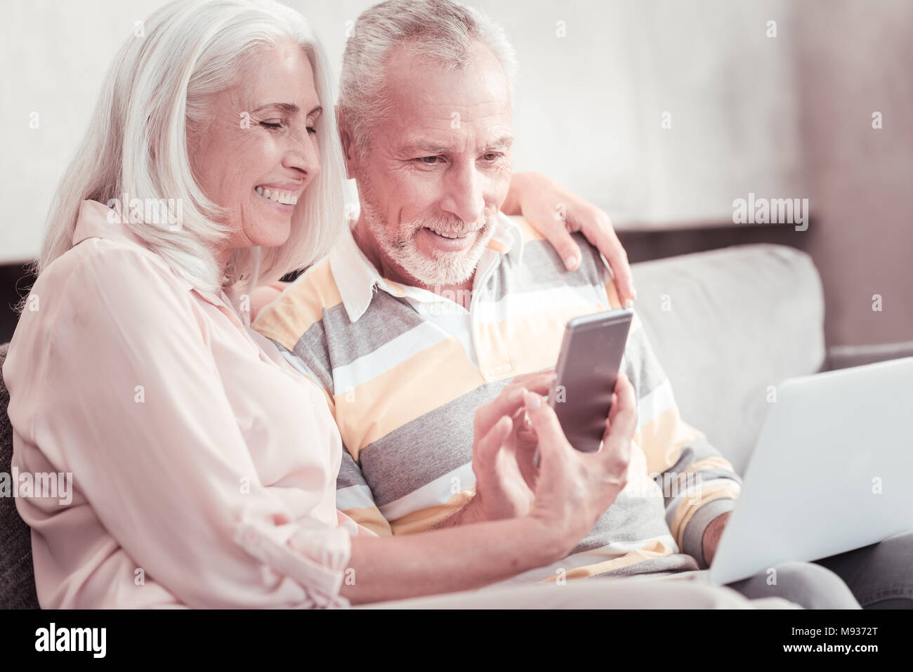 Freudige smart Paar lächelnd und mit Blick auf das Smartphone. Stockfoto