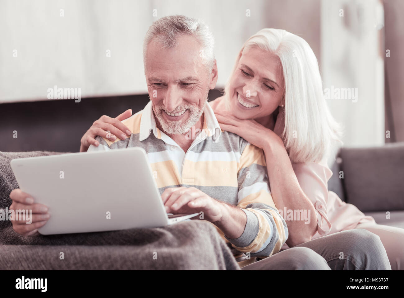 Interessierte im Alter von Paar lächelnd und Arbeiten mit dem Laptop. Stockfoto