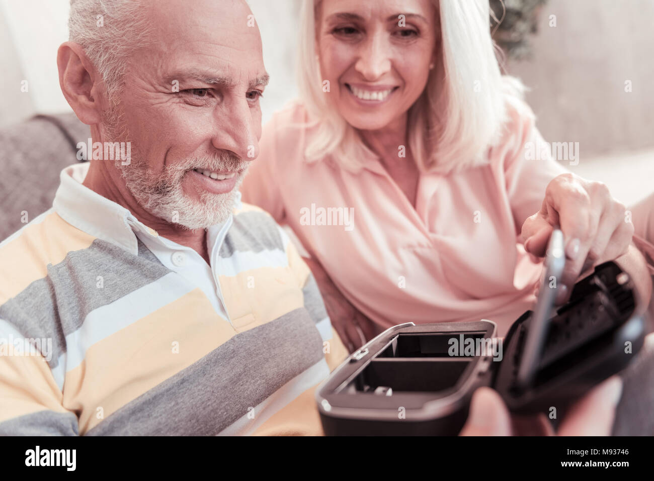 Senior angenehmes Paar sitzen und Verkostung der Minianwendung. Stockfoto