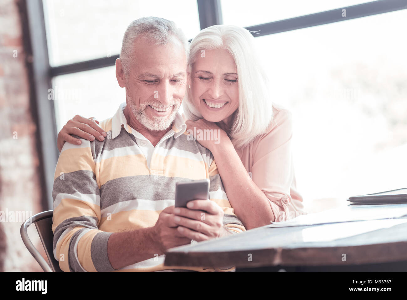 Zufrieden nettes Paar lächelnd und mit Blick auf das Smartphone. Stockfoto
