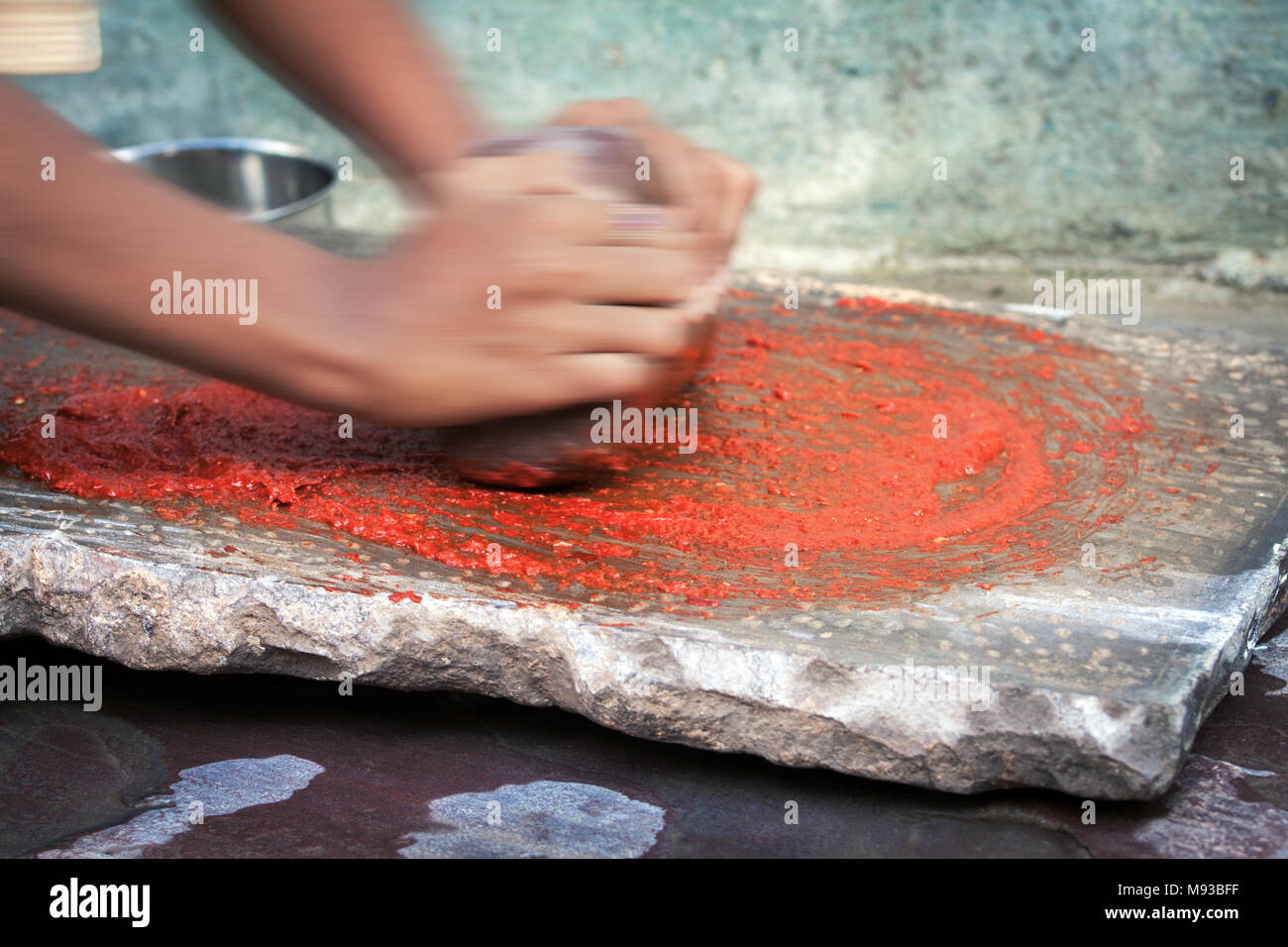 Chili Paste in der Entscheidungsfindung, Bewegungsunschärfe, die Hände. Indisches Mädchen Vorbereitung Würze mit Schleifstein rote Chilis in einem Chili Paste in Indien zu schleifen Stockfoto
