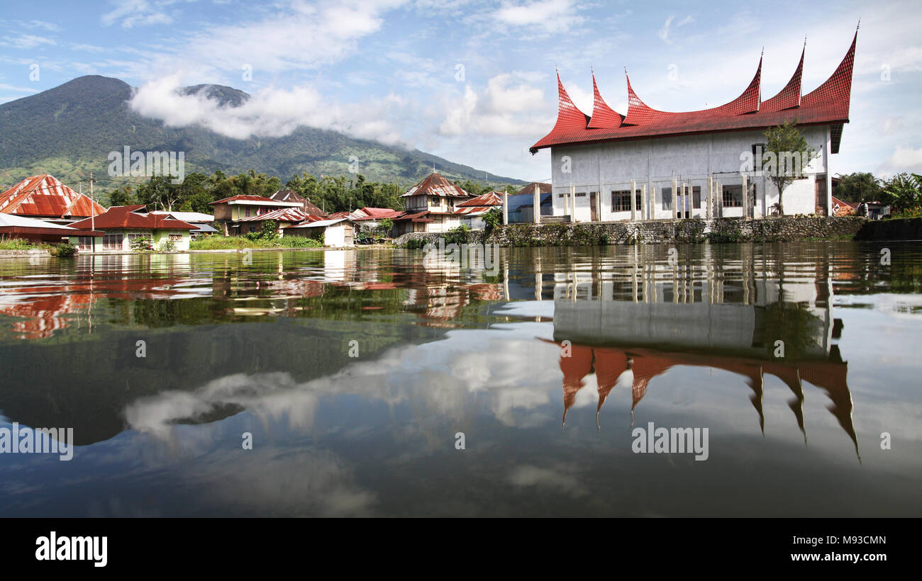 Landschaft von Sumatra. Atemberaubende Aussicht auf Mount Merapi aus über einen See mit Minangkabau haus dach Stil im Wasser spiegelt. Symmetrische Spiegelbild Stockfoto