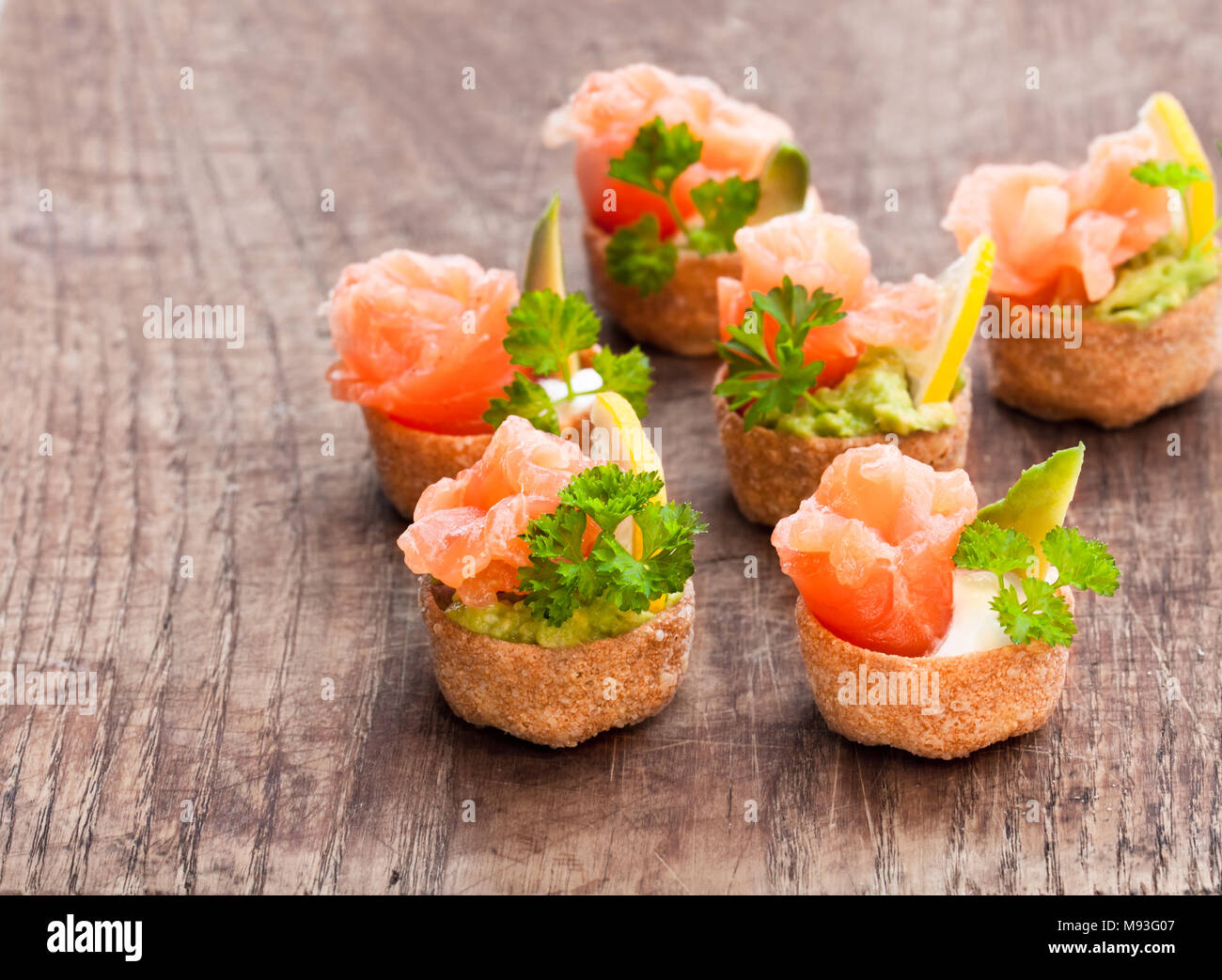 Croustades knuspriges Gebäck Fälle mit gesalzenen Lachs und Avocado auf hölzernen Tisch gefüllt Stockfoto