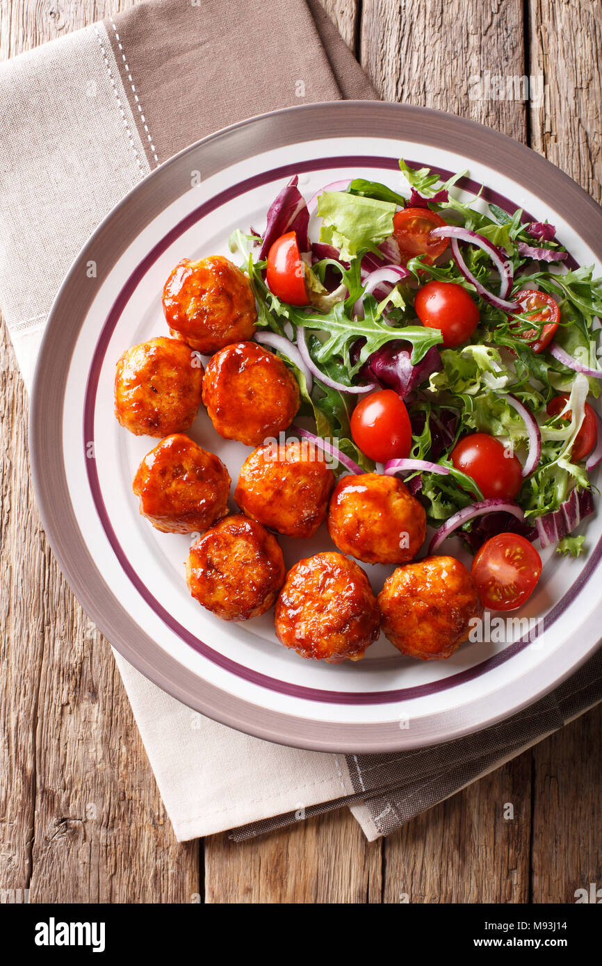 Leckeres Essen: Fried Chicken Frikadellen Salat von Tomaten, Salat und Zwiebeln close-up auf einem Teller auf den Tisch. Vertikal oben Ansicht von oben Stockfoto