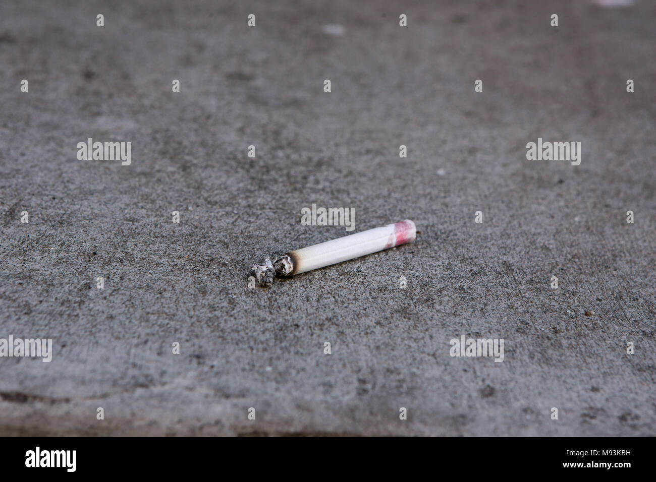 Ein Lippenstift Flecken, Lit, filterlose Zigarette, liegen auf dem Beton. Stockfoto