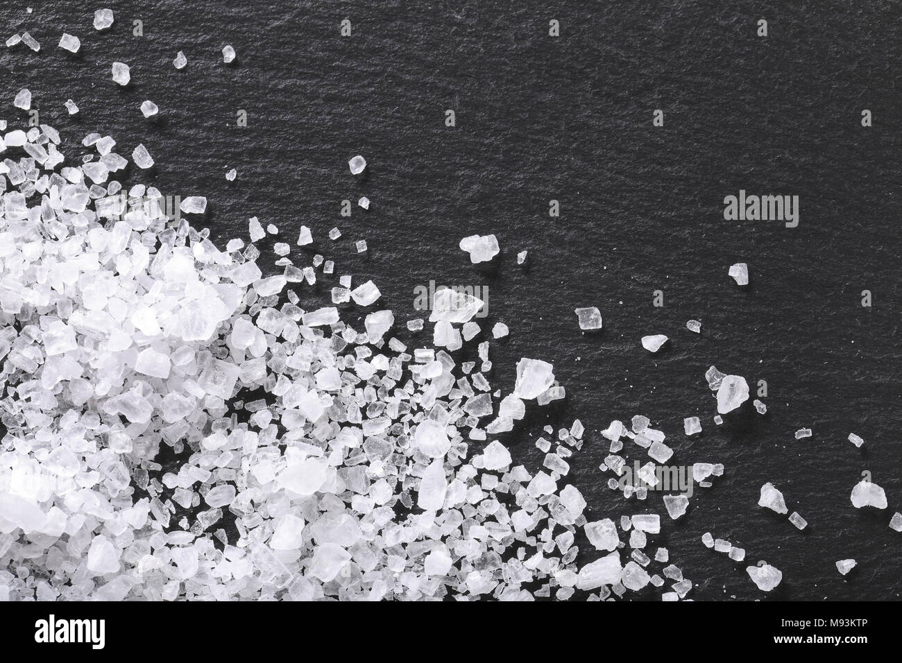 Kristalle von grobkörnigem Meersalz auf schwarzem Hintergrund Stockfoto
