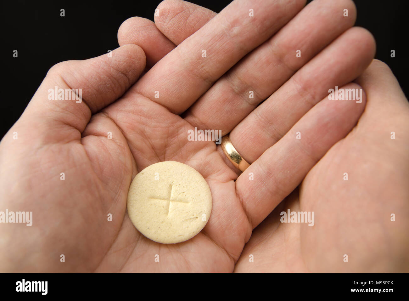 Hohlen Hände von einem Mann mit einem Wafer aus Brot der Leib Christi beim Empfang der Kommunion an einem Römisch-katholischen Messe Stockfoto