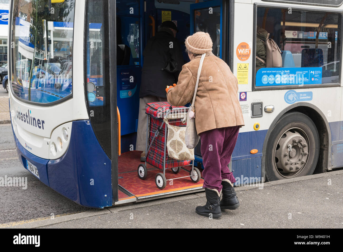 Ältere Frau einen Bus mit einer fahrbaren Einkaufswagen in England, Großbritannien. Stockfoto