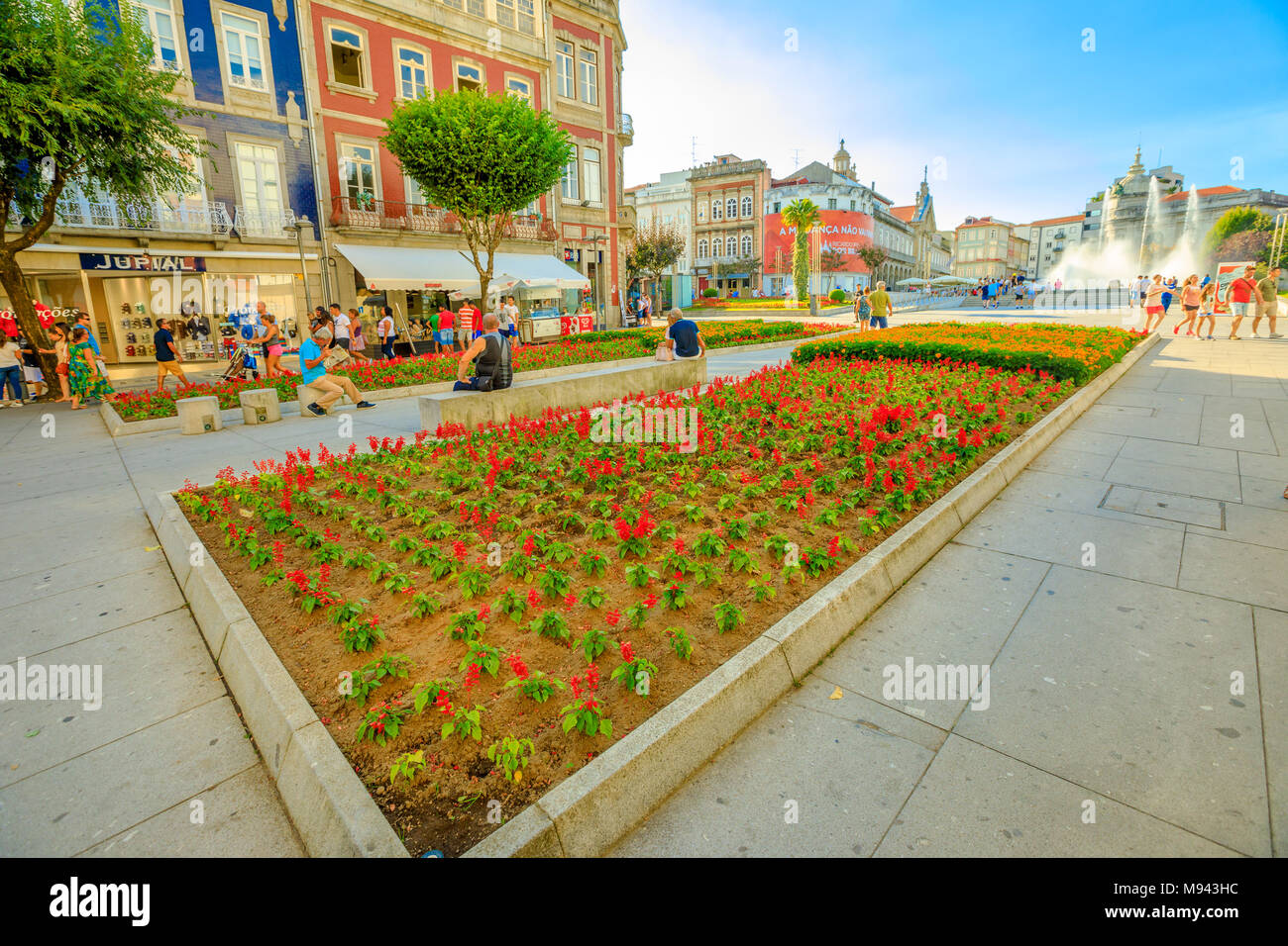 Braga, Portugal - 12. August 2017: Blumenbeeten und touristische Wandern in der Avenida da Liberdade, einer der wichtigsten Straßen von Braga, Überschreiten der Praça da Republica als Arcade bekannt mit ihren Brunnen. Stockfoto