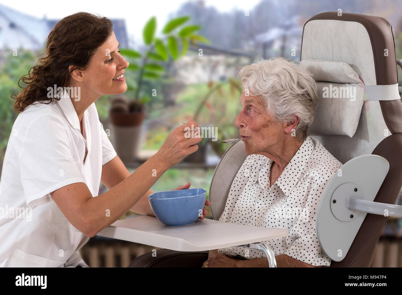 Behinderte Mitarbeiter erhält eine Home Meal Delivery und durch einen Arbeitnehmer oder eine Krankenschwester vor der Fenster in den Garten eingezogen Stockfoto