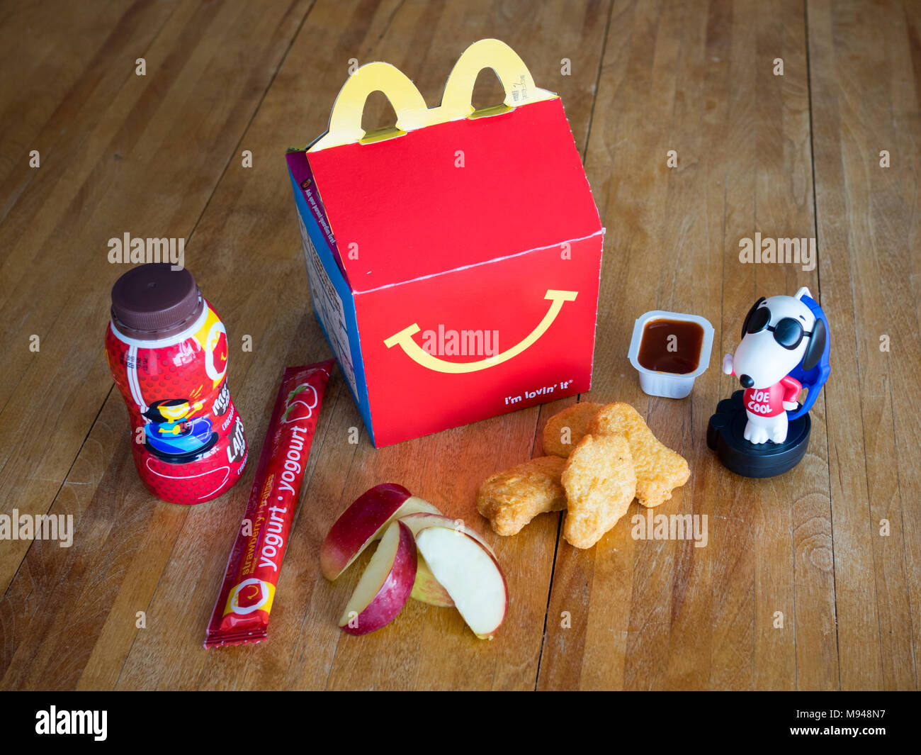 Ein McDonald's Happy Meal mit Chicken McNuggets, Apple Keile, Schokolade, Milch, Joghurt, und Snoopy Spielzeug. Stockfoto