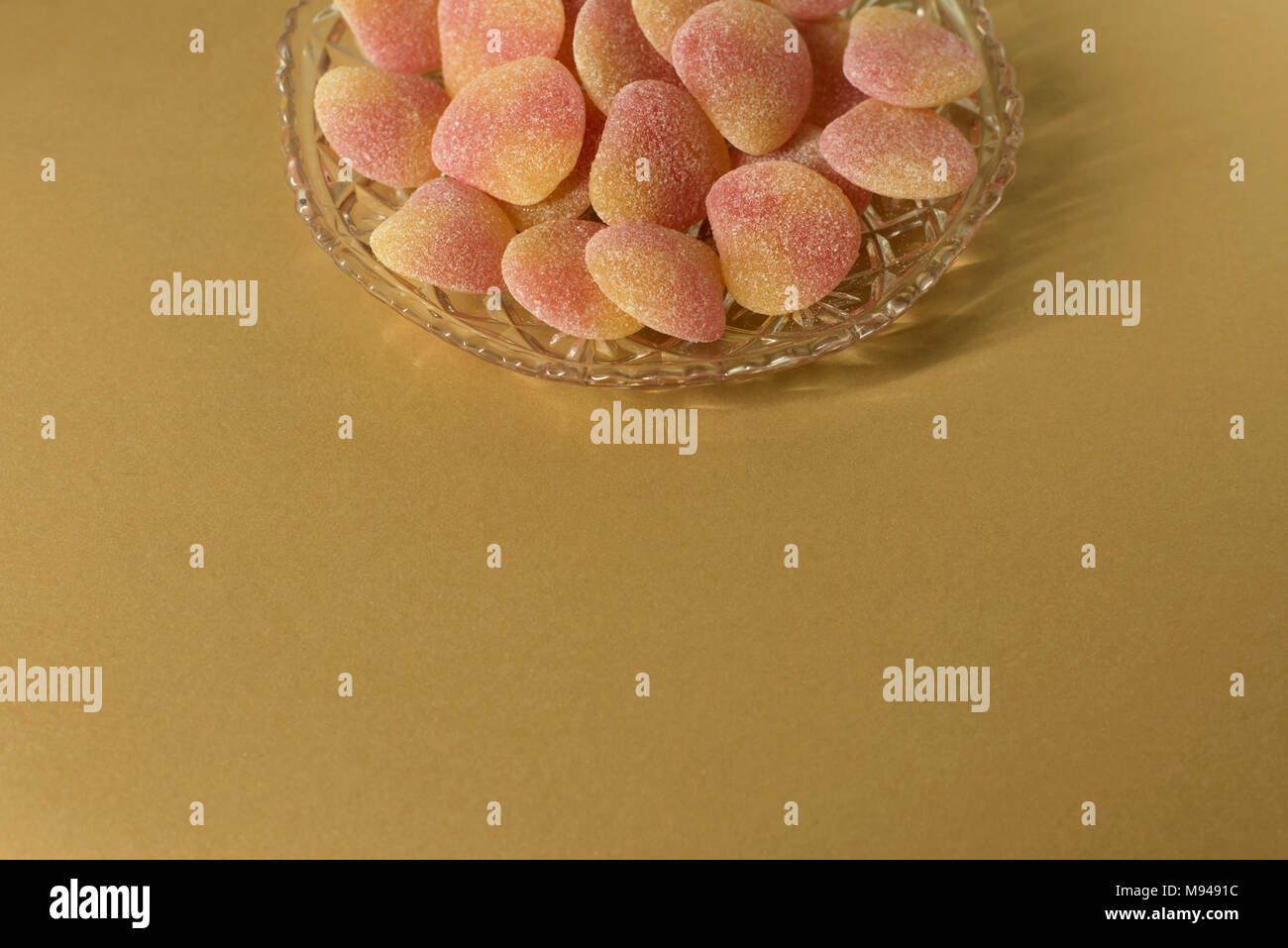 Gezuckerte gelee Süßigkeiten in Kristall Glas Teller - auf minimale gold background-centered design Element, kopieren Raum Stockfoto