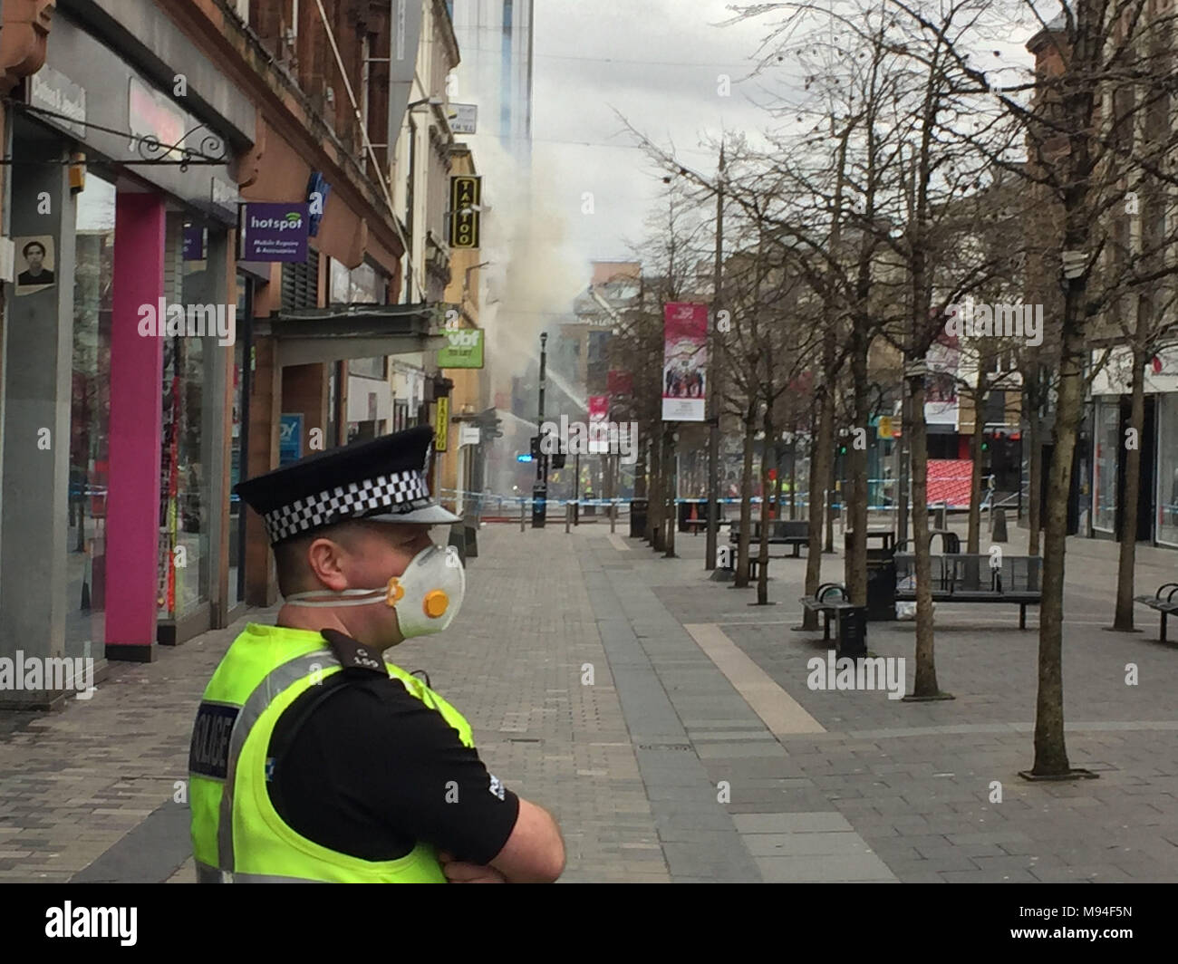 Ein Polizist trägt eine Maske an der Szene im Stadtzentrum von Glasgow, wo die Feuerwehrleute, die sich mit einer großen blesse Sauchiehall Street in der Nähe der Kreuzung mit der Hope Street. Stockfoto